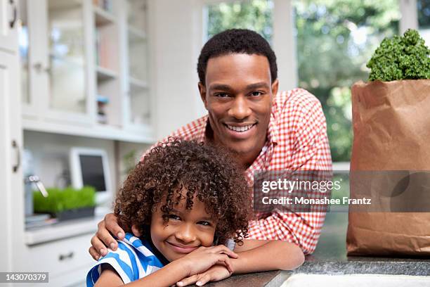 father and son unpacking groceries in kitchen - young man groceries kitchen stock pictures, royalty-free photos & images