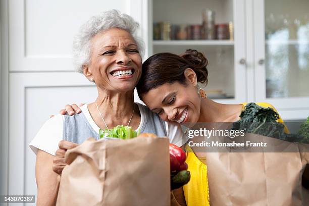 mother and daughter unpacking groceries in kitchen - healthy eating seniors stock pictures, royalty-free photos & images