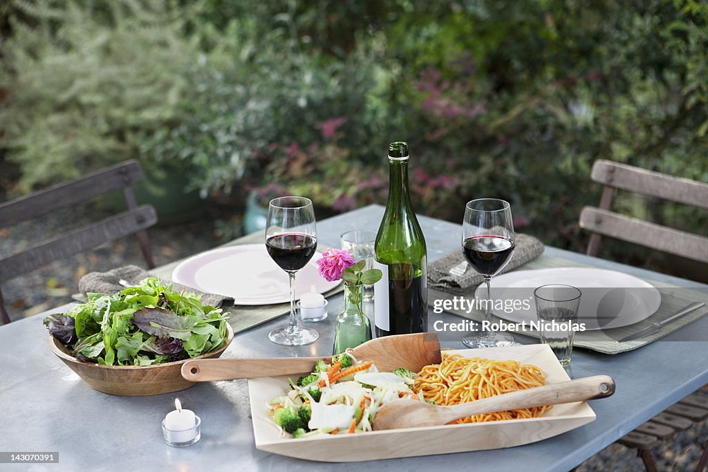 Salad and pasta on set table outdoors