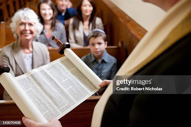 rabbi reading from torah scrolls in synagogue - jewish people stockfoto's en -beelden