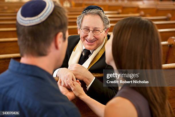 couple talking with rabbi in synagogue - skull cap stock pictures, royalty-free photos & images