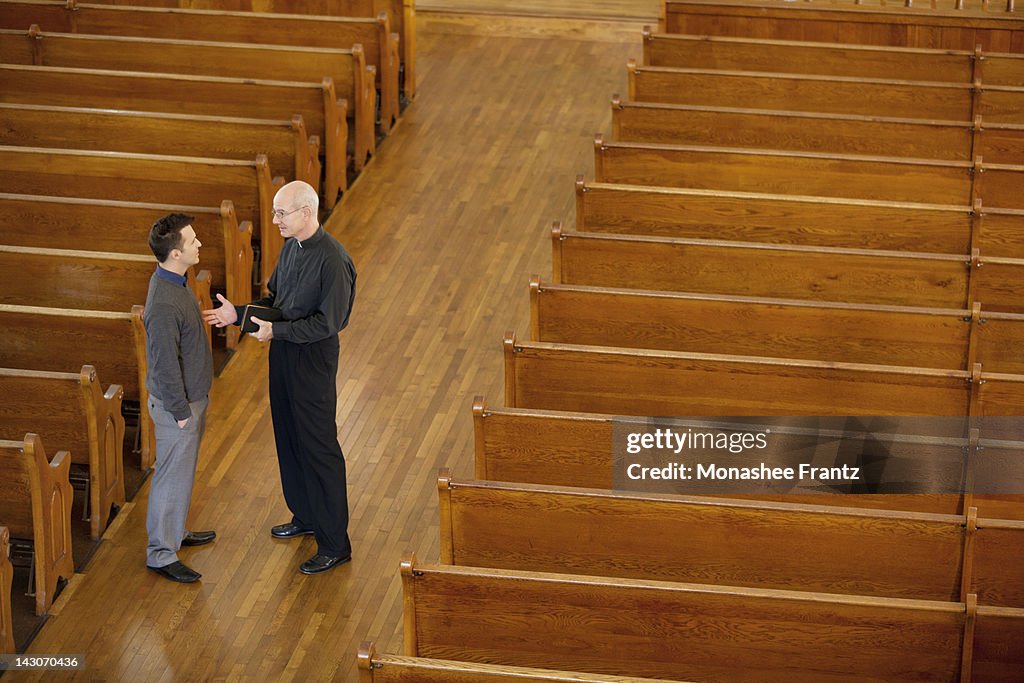 Priest talking with man in church
