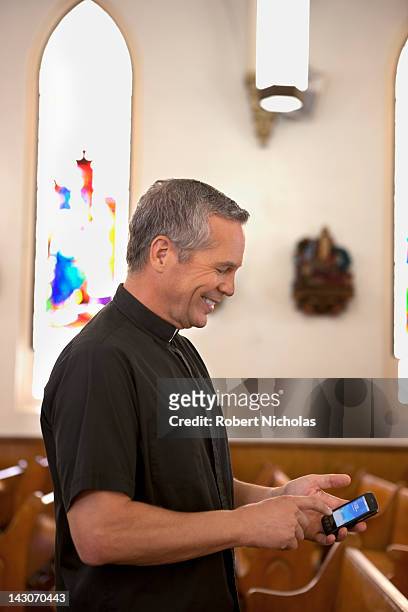 priest using cell phone in church - priests talking stock pictures, royalty-free photos & images