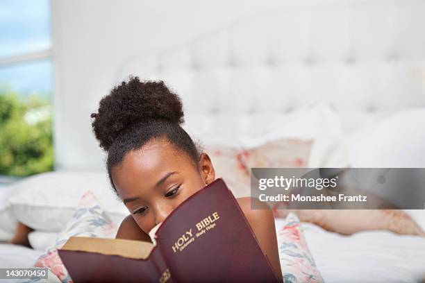 girl reading bible in bed - reading bible in bed photos et images de collection