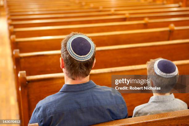 father and son in yarmulkes sitting in synagogue - jewish people ストックフォトと画像