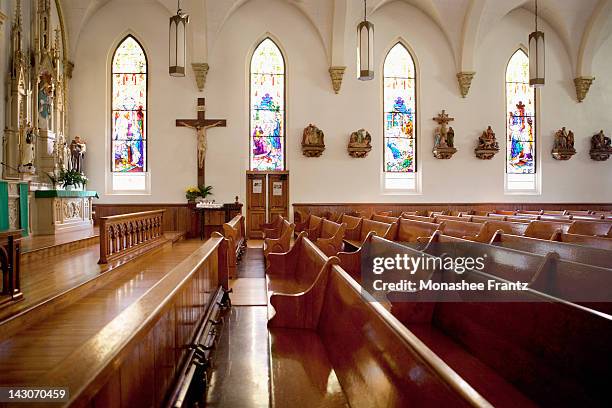 pews and stained glass windows in church - katholicisme stockfoto's en -beelden