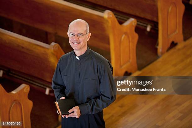 smiling priest standing in church - minister clergy ストックフォトと画像