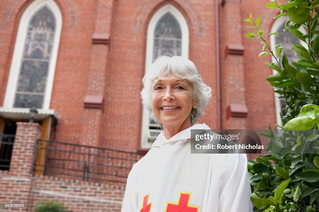 Smiling reverend standing outside church