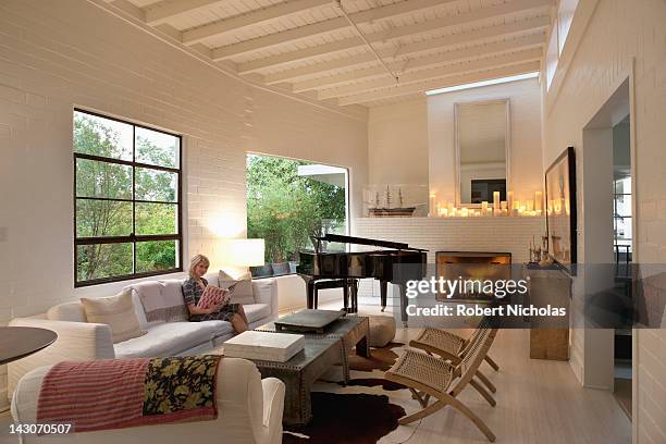 woman reading in modern living room - modelwoning stockfoto's en -beelden