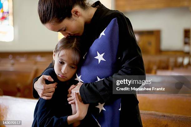 mother and daughter hugging at military funeral - funeral fotos stock-fotos und bilder