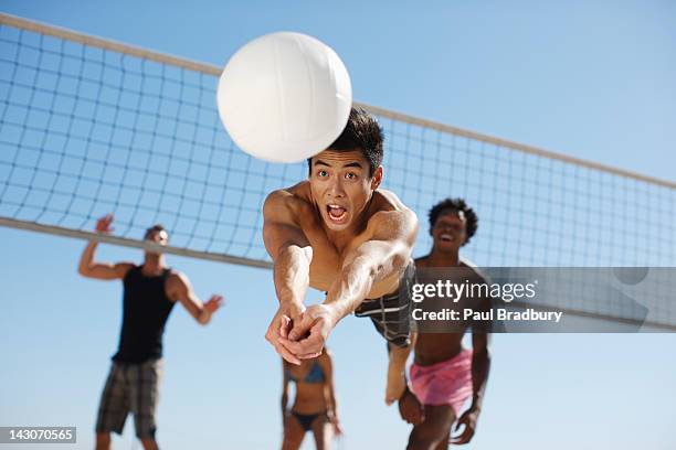 mann tauchen für volleyball am strand - volleyball netz stock-fotos und bilder