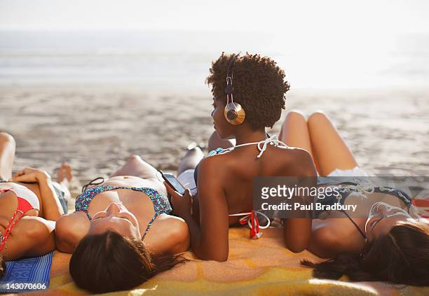 women sunbathing together on beach - zomer muziek stockfoto's en -beelden