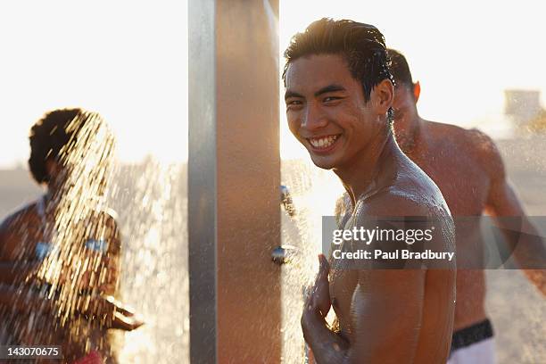 men in swimsuits showering on beach - shower man woman washing stock pictures, royalty-free photos & images