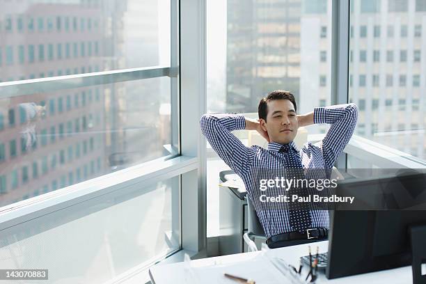 businessman relaxing at desk in office - hands behind head stock pictures, royalty-free photos & images