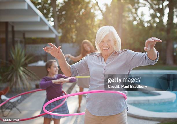mujer de edad avanzada hooping de hula en el patio - vida activa fotografías e imágenes de stock