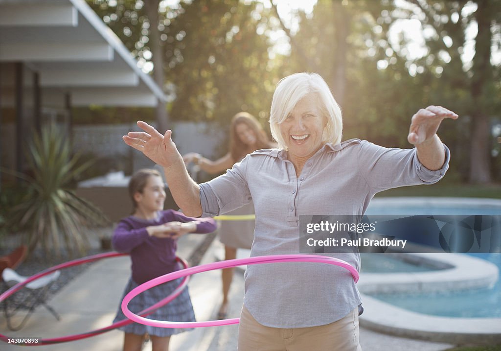 Older woman hula hooping in backyard