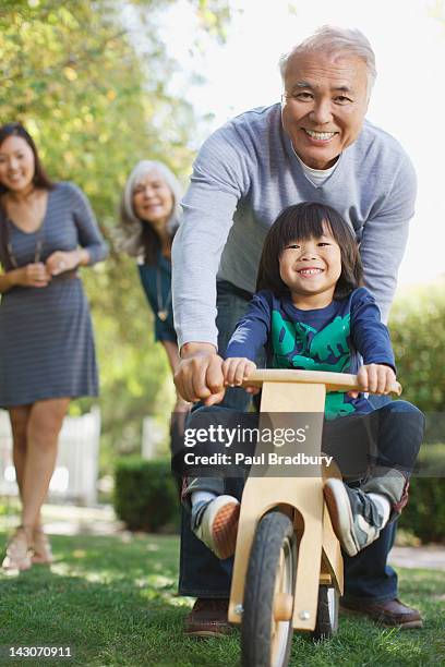 older man pushing grandson in backyard - asian smiling father son stock pictures, royalty-free photos & images