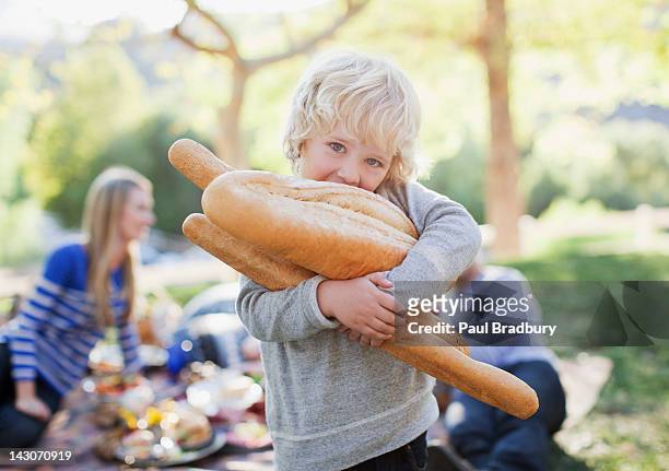 boy holding loaves of bread outdoors - eating bread stockfoto's en -beelden