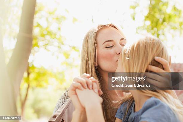 mother kissing daughter outdoors - no face stock pictures, royalty-free photos & images