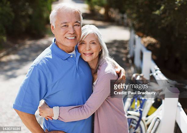 smiling older couple relaxing outdoors - active seniors asian stock pictures, royalty-free photos & images