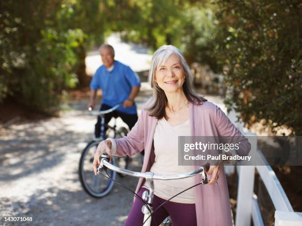 smiling older couple riding bicycles - japanese senior couple stockfoto's en -beelden