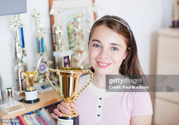 smiling girl holding trophy in bedroom - cas awards stock pictures, royalty-free photos & images