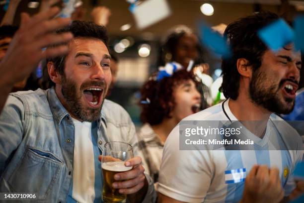 group of argentine soccer fans chanting and cheering for national team at sports bar - crowd cheering bar stock pictures, royalty-free photos & images