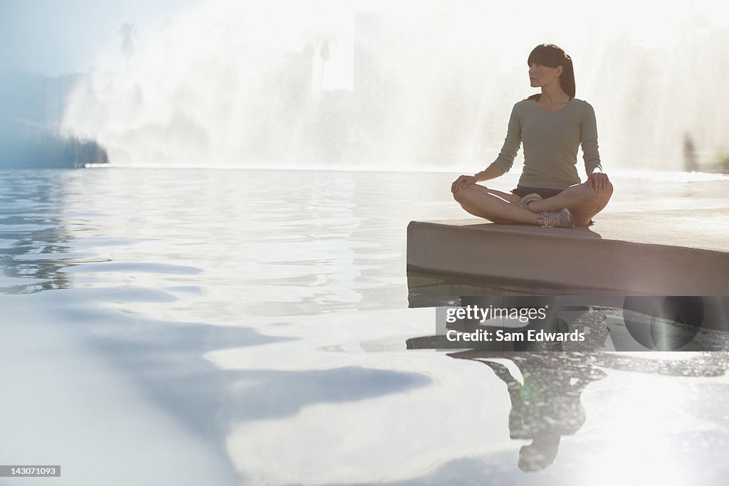 Woman meditating by still pool