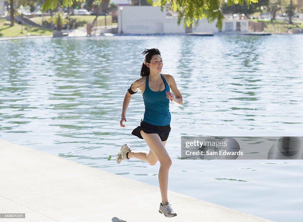 Woman running along lake in park