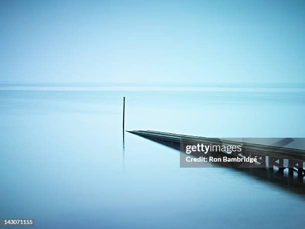 pier jutting out into still lake - boat launch stockfoto's en -beelden