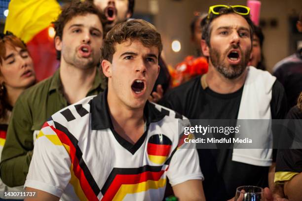 group of german sports fans chanting and cheering for national football team at sports bar - chanting stock pictures, royalty-free photos & images
