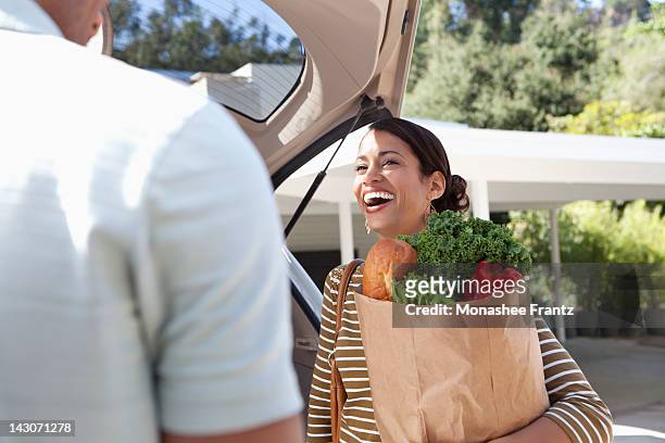 woman unloading groceries from car - domestic car stock-fotos und bilder