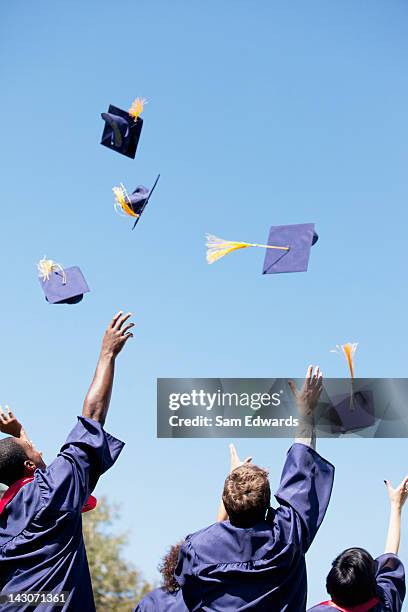 graduates throwing caps in air outdoors - sam day stockfoto's en -beelden