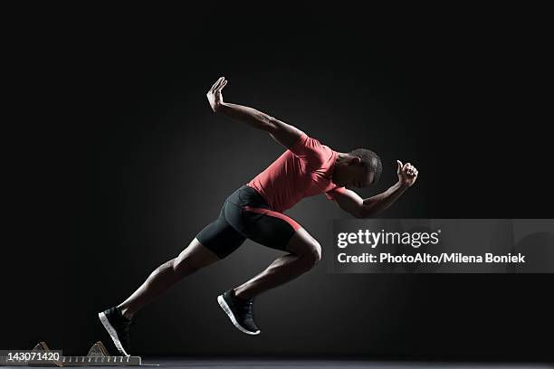 male athlete leaving starting block - men's track stockfoto's en -beelden