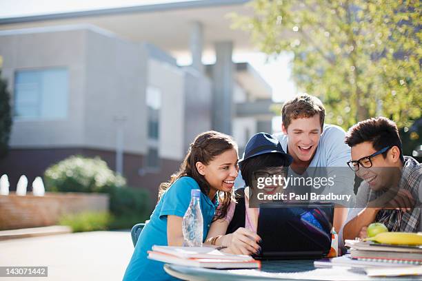 estudiantes usando la computadora portátil juntos al aire libre - college campus students fotografías e imágenes de stock