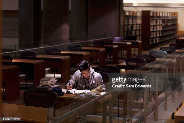 student working in library at night - universiteit stockfoto's en -beelden