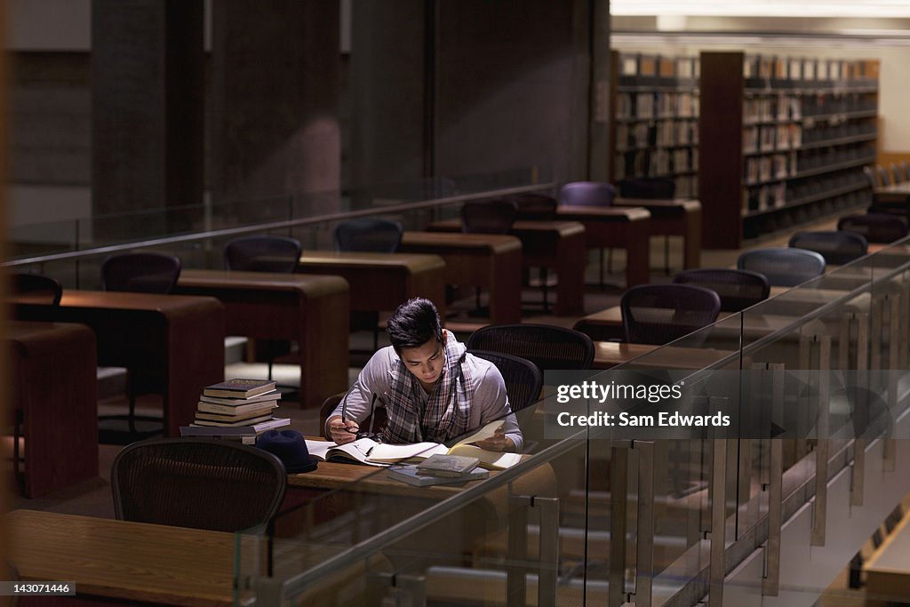 Aluno trabalhando em biblioteca à noite