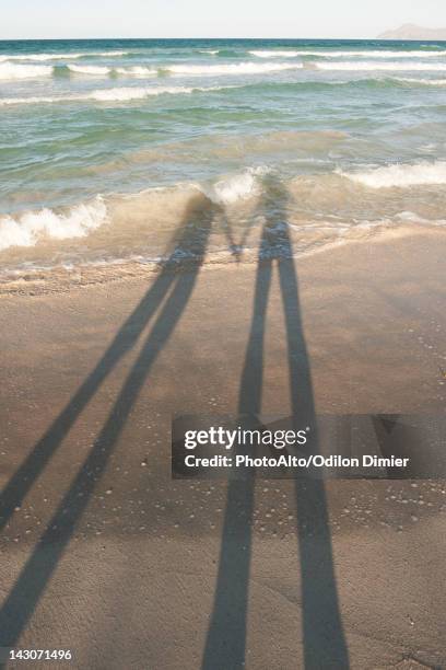 shadows of couple on beach - islas baleares fotografías e imágenes de stock
