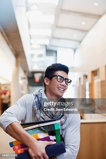 student carrying stack of books in library - college males stock pictures, royalty-free photos & images