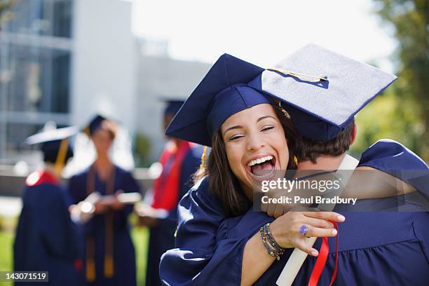 sonriendo egresados, que abrazan al aire libre - graduation gown fotografías e imágenes de stock