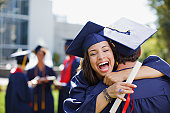 Smiling graduates hugging outdoors
