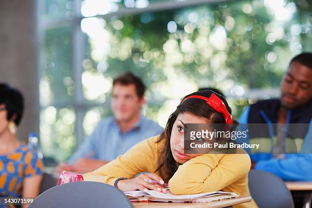 student resting head on desk in classroom - bored student stock pictures, royalty-free photos & images