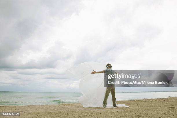 man trapped in plastic on beach - tarpaulin stock pictures, royalty-free photos & images