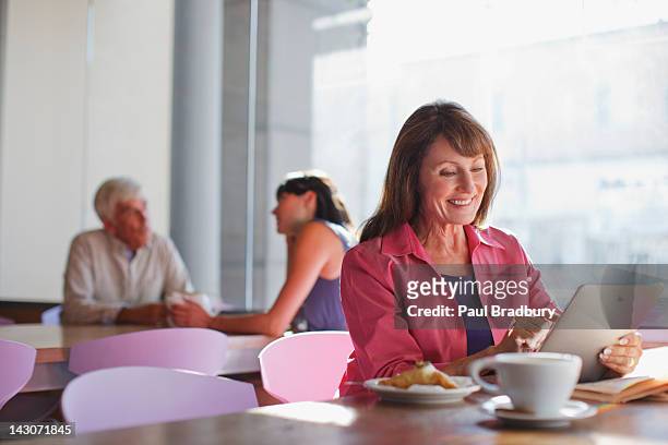 woman using tablet computer in cafe - senior women cafe stock pictures, royalty-free photos & images