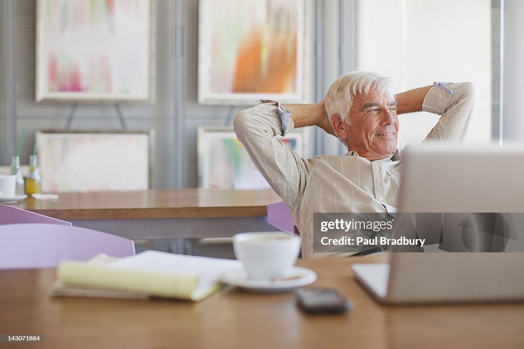 Older man using laptop in cafe
