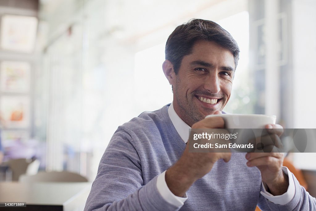 Smiling man drinking coffee in cafe