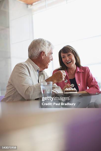 older couple sharing dessert in cafe - old couple restaurant stockfoto's en -beelden