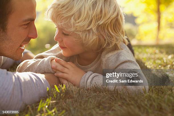 father and son laying in grass together - proud parent stock pictures, royalty-free photos & images