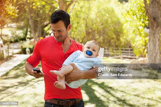 father with baby using cell phone - samuser stock pictures, royalty-free photos & images