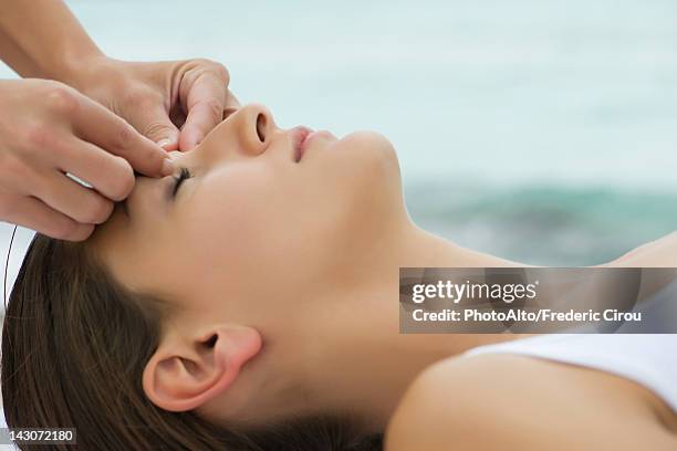 young woman receiving face massage, side view - shiatsu stock pictures, royalty-free photos & images